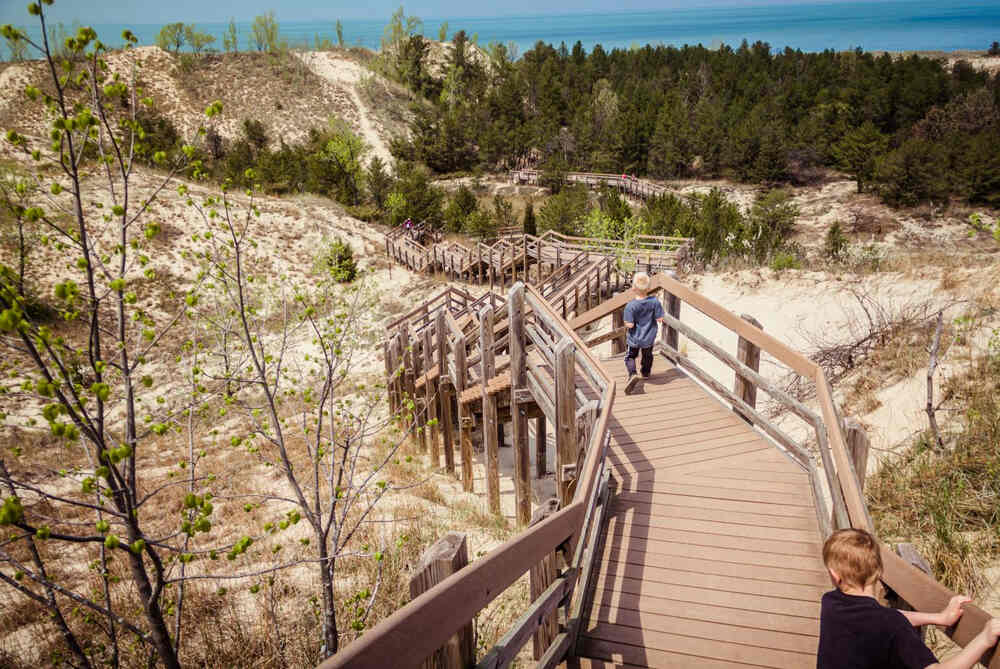 Two children enjoy a hike climbing down a boardwalk trail inside indiana dunes np