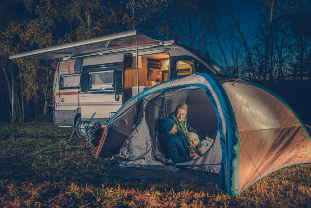 A family comes well-prepared for a night camping outdoors, equipped with a sealed tent and warm clothing