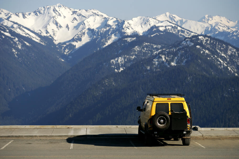 A camper van is parked alongside Hurricane Ridge Road as it faces an incredible view of the snow-capped Olympic Mountains