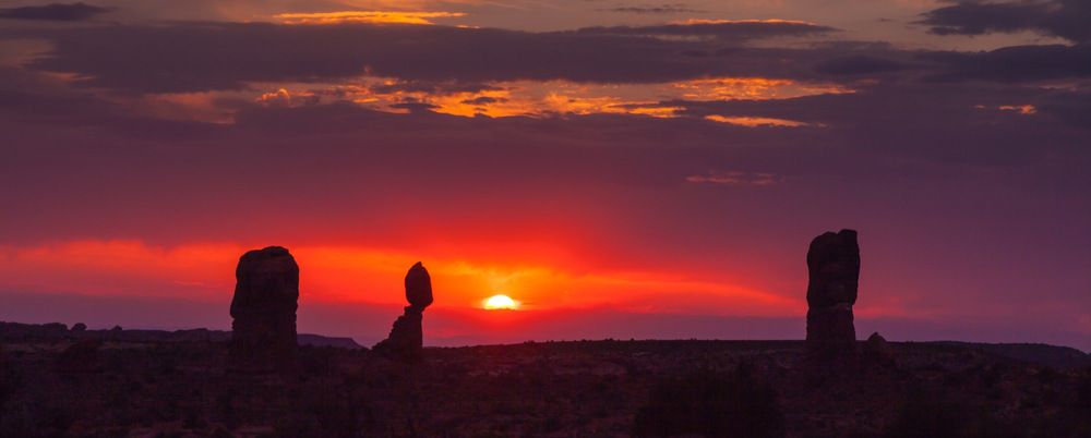 sunset over Arches National Park as the towering Balanced Rock looms in the background