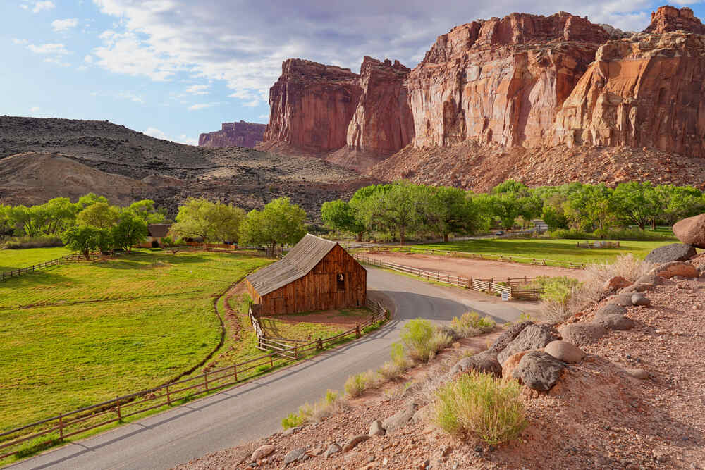 the Gifford Barn in Capitol Reef National Park with trees and mountains in background, a historic structure located in the Fruita Historic District